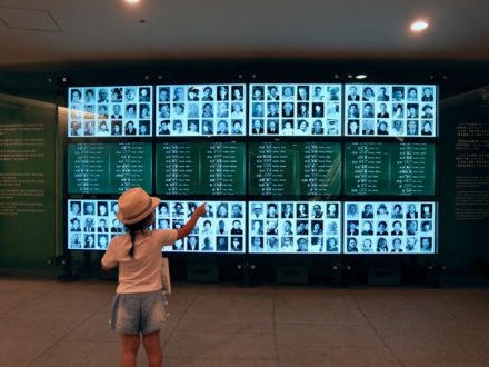 bambina davanti alle immagini delle vittime della bomba atomica.